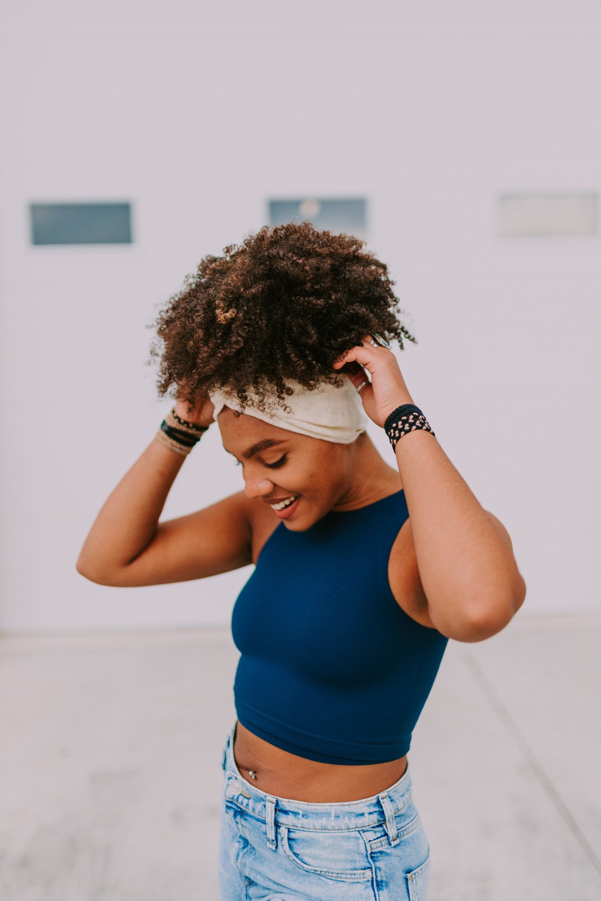 A woman wearing a headband and a crop top is smiling.