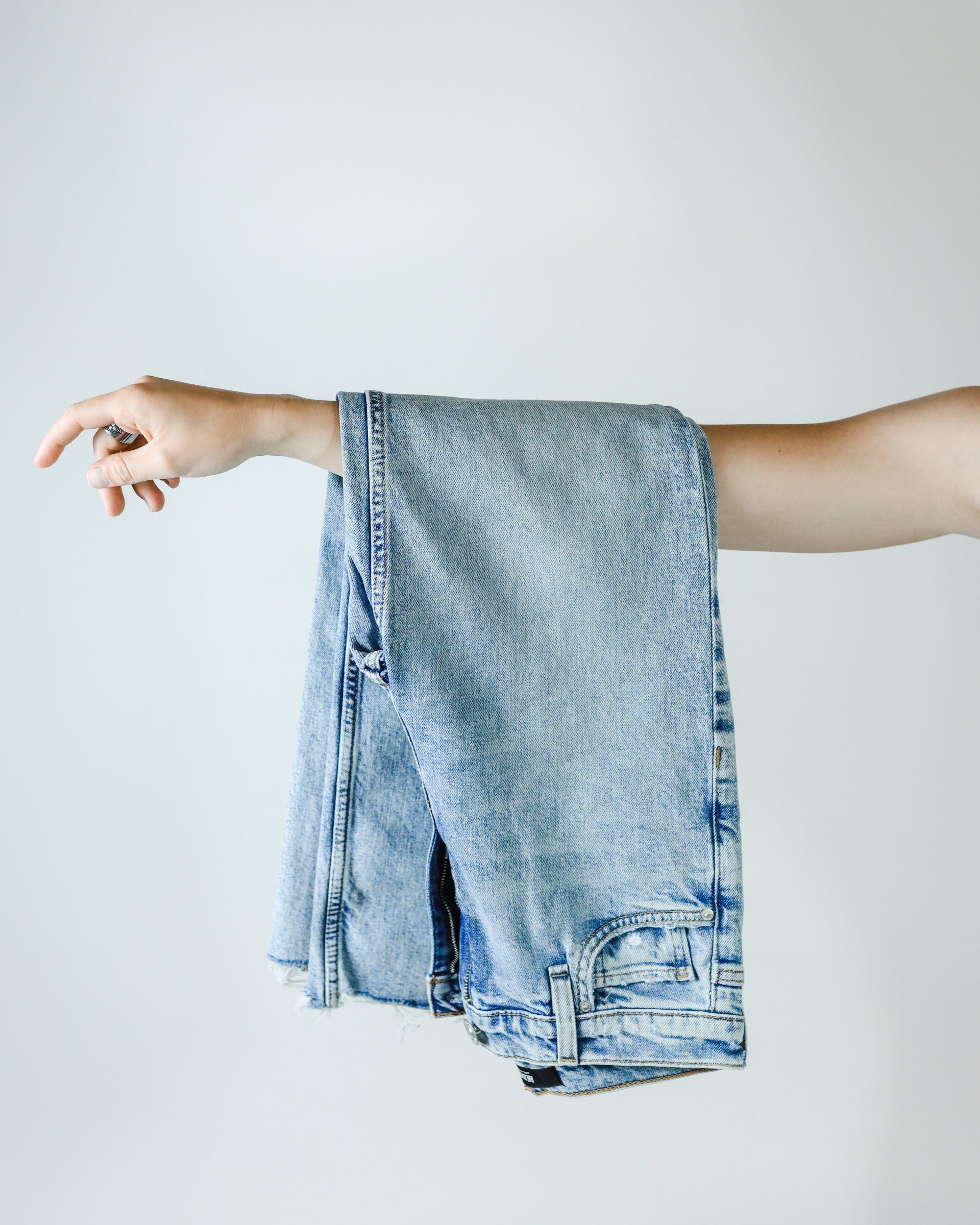 A person is holding a pair of jeans in their hand.