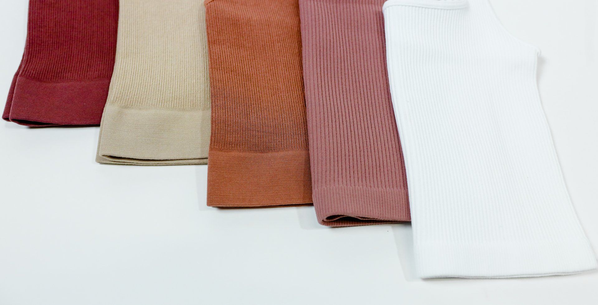 A row of different colored towels are lined up on a white surface.