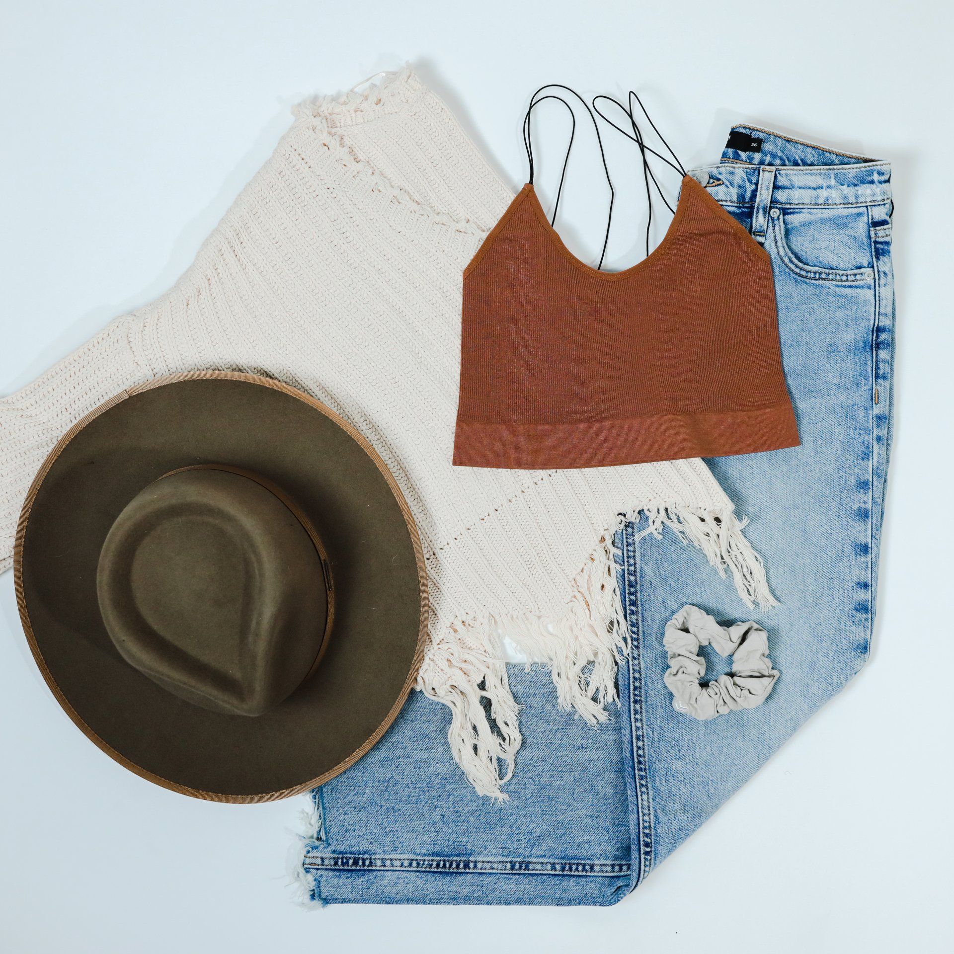 A hat a crop top a sweater and jeans are laid out on a table