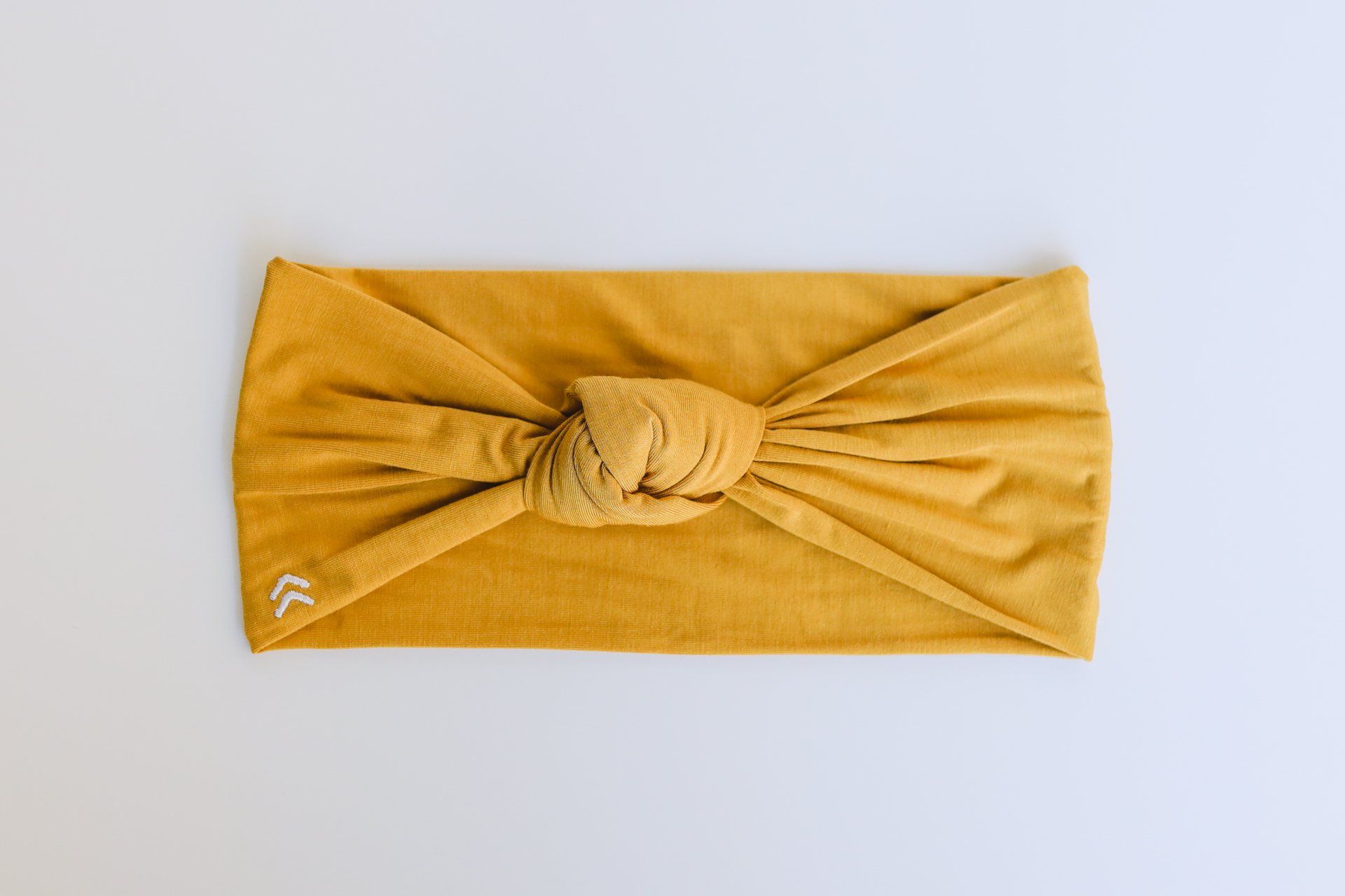 A yellow headband with a knot in the middle is on a white surface.