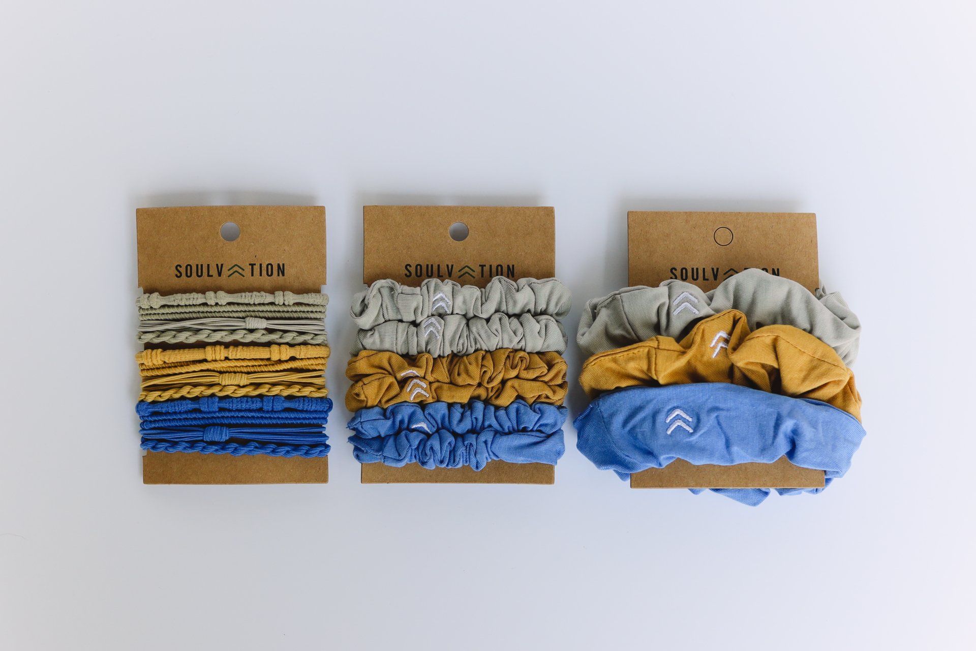 Three scrunchies are sitting on top of each other on a white surface.