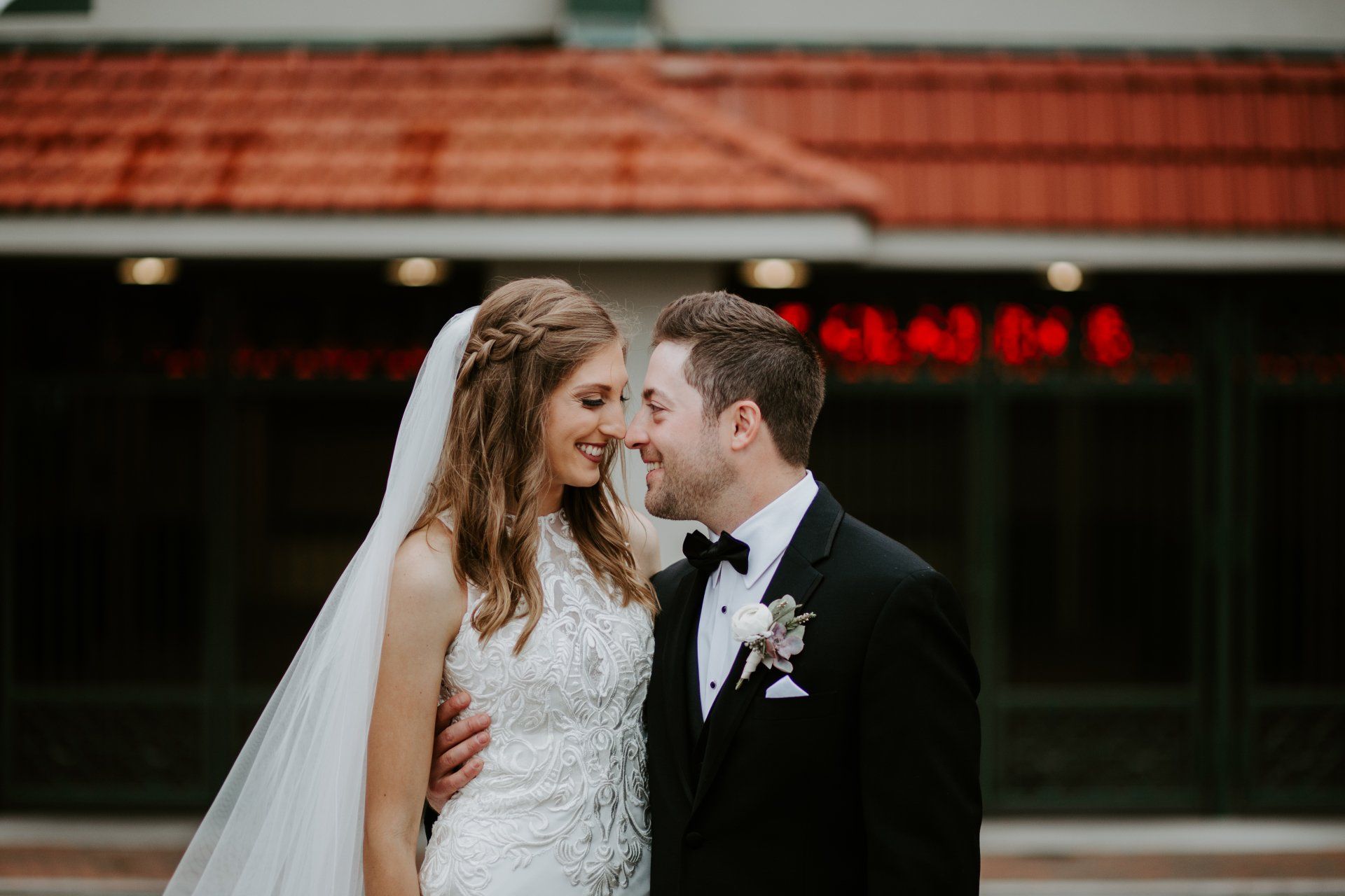 A bride and groom are kissing in front of a building.