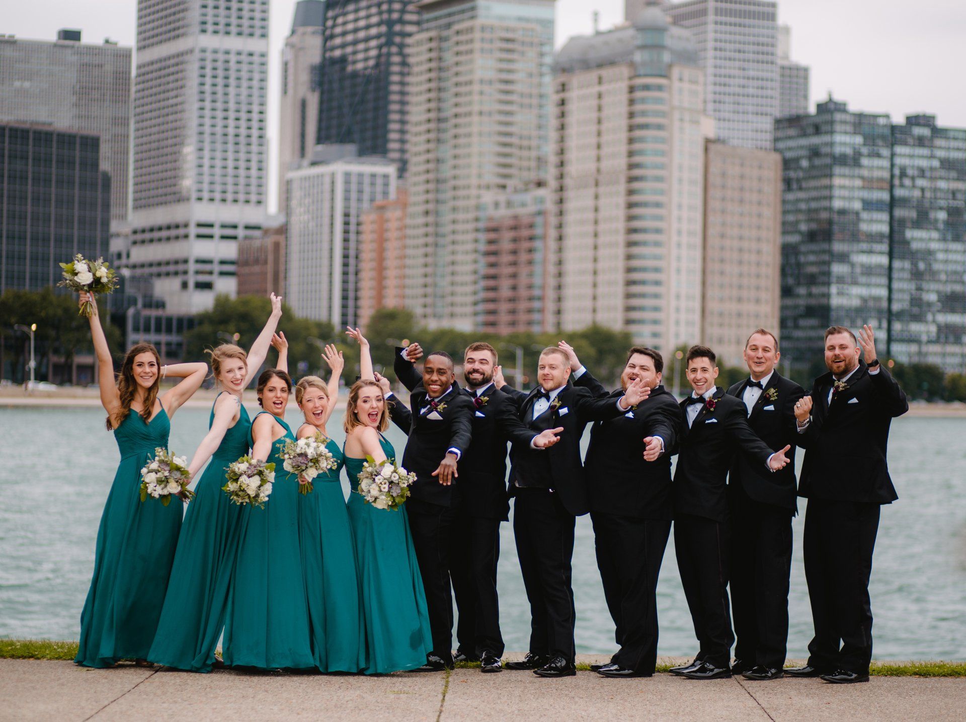 A wedding party is posing for a picture in front of a city skyline.