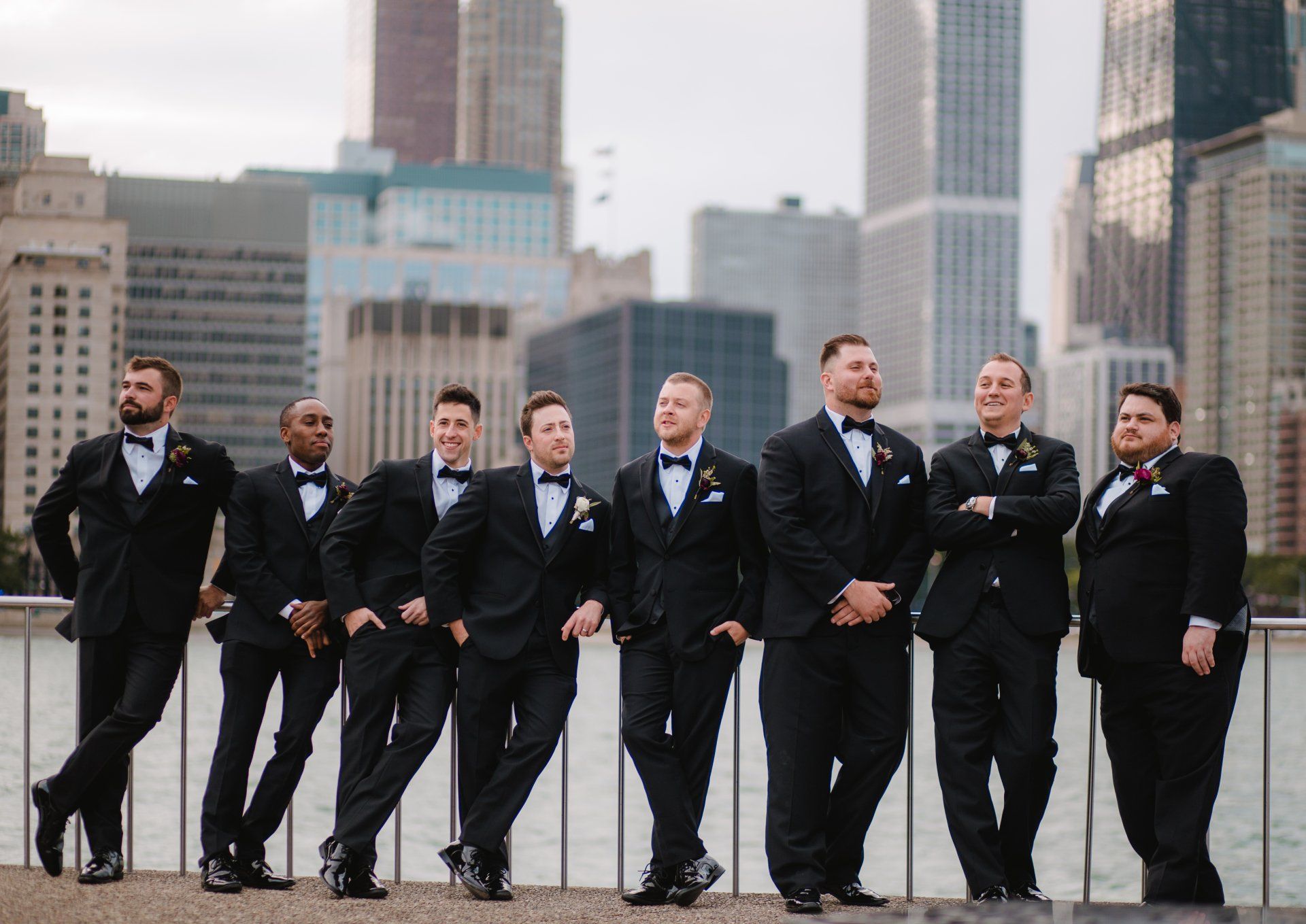 The groom and his groomsmen are posing for a picture in front of a city skyline.