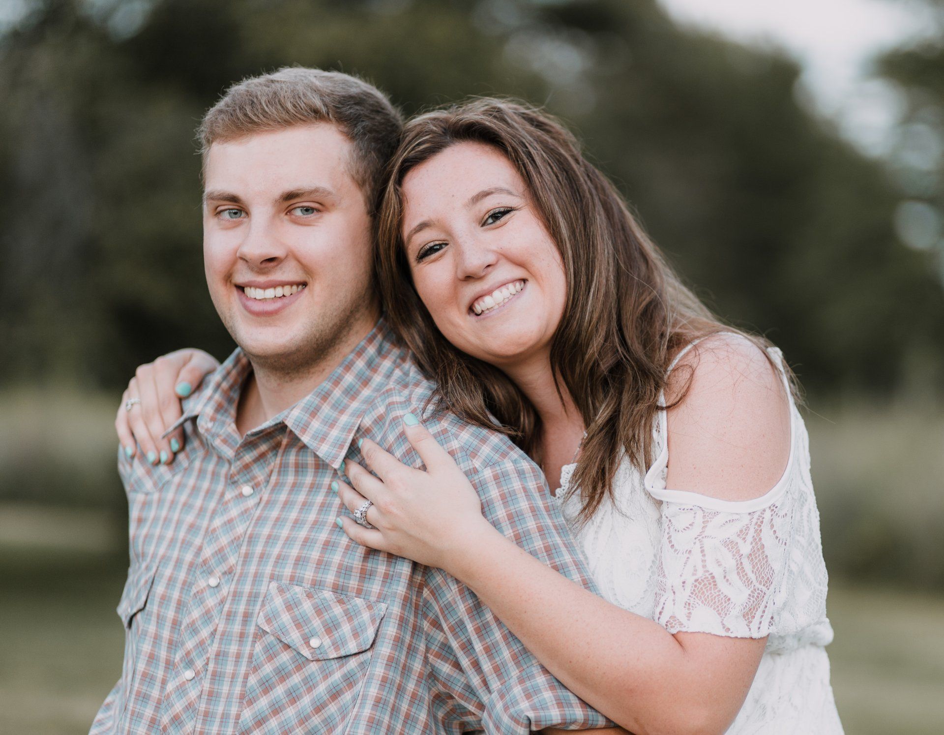 A man and a woman are posing for a picture in a field.