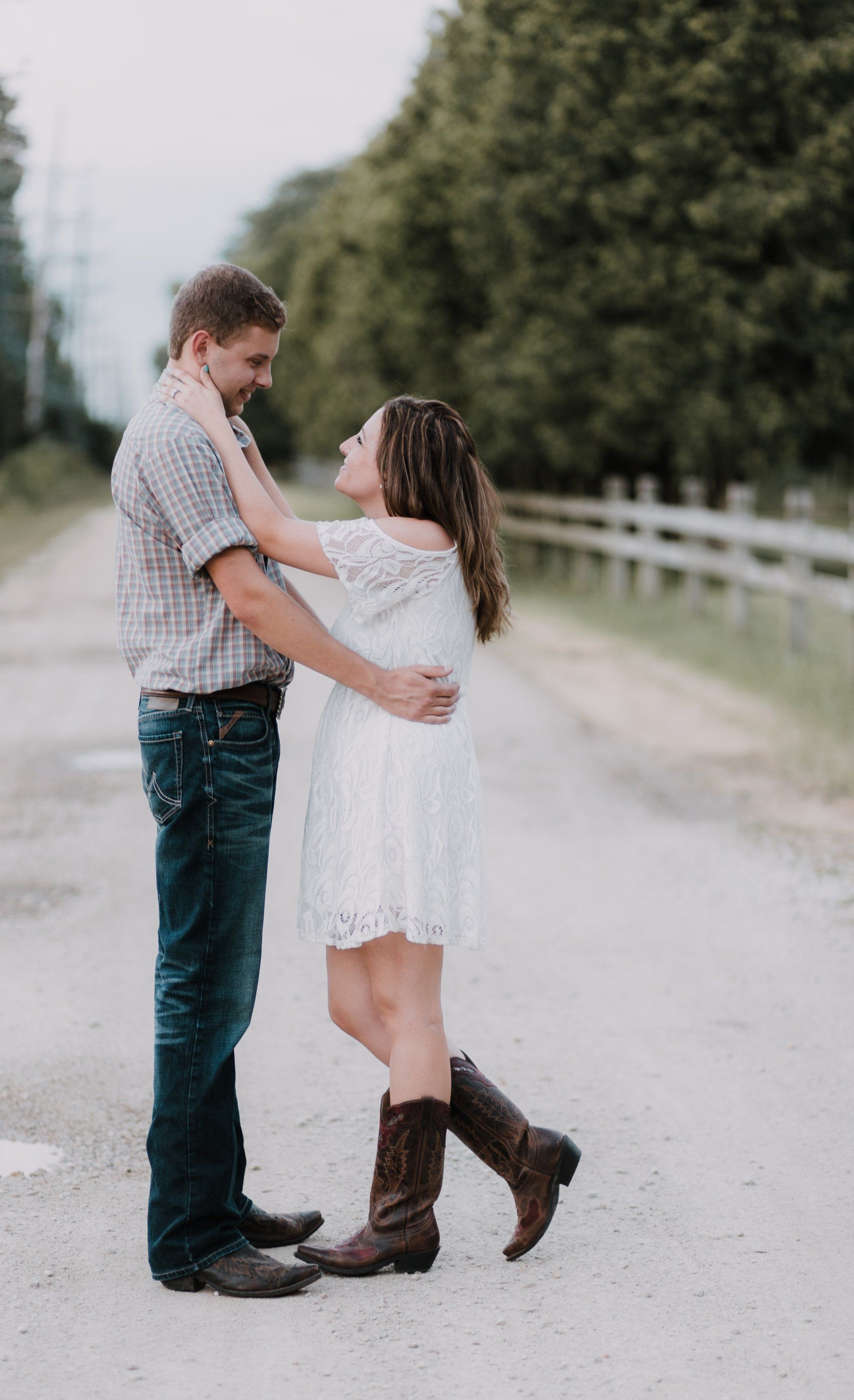 A man and a woman are standing next to each other on a dirt road.
