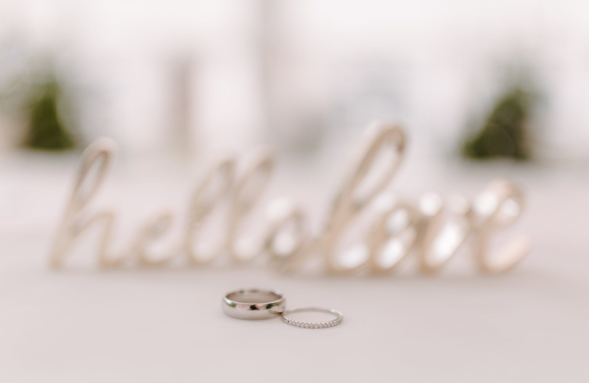 A couple of wedding rings sitting in front of a sign that says `` hello love ''.