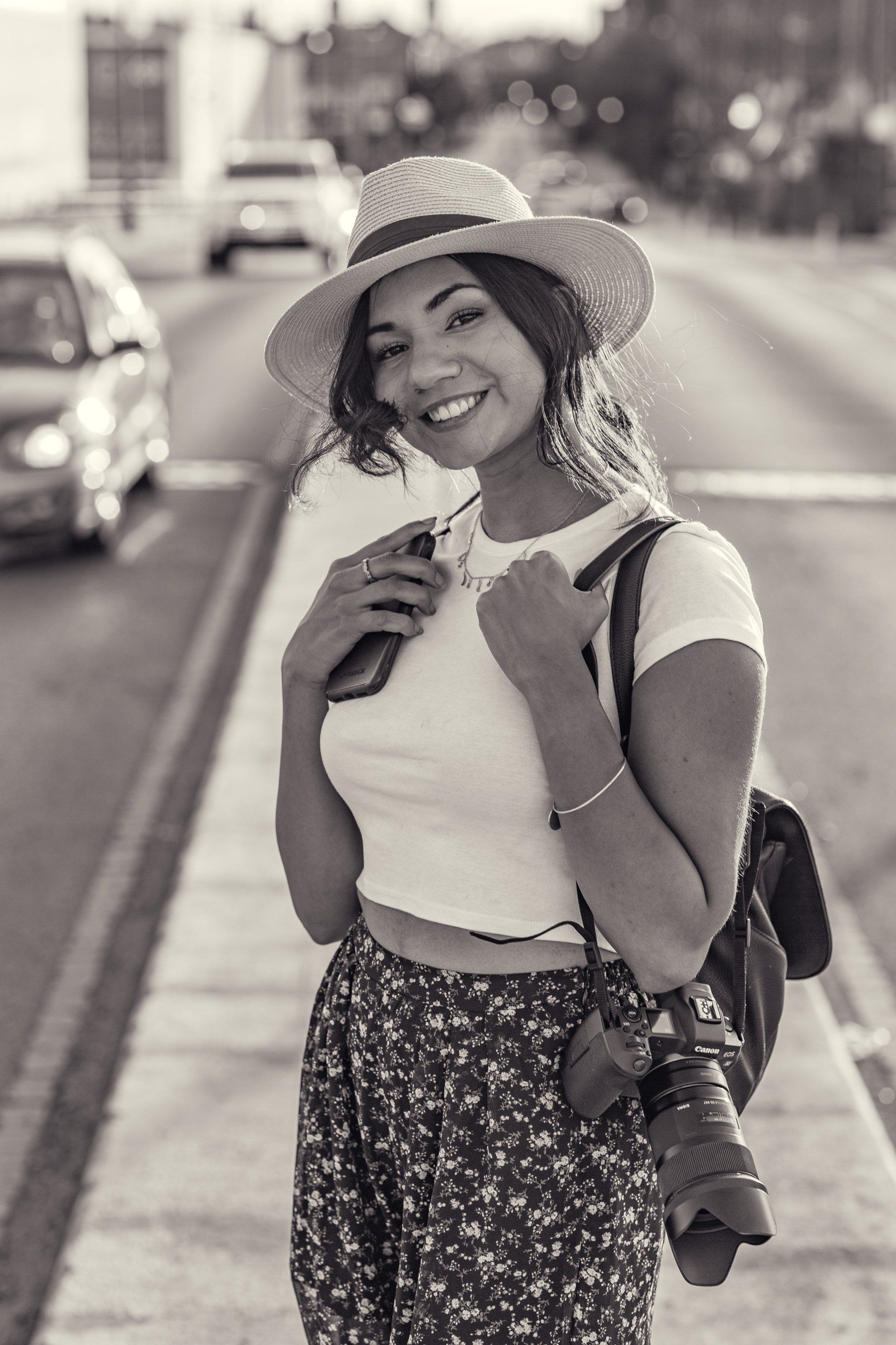 A black and white photo of a woman wearing a hat and holding a camera.
