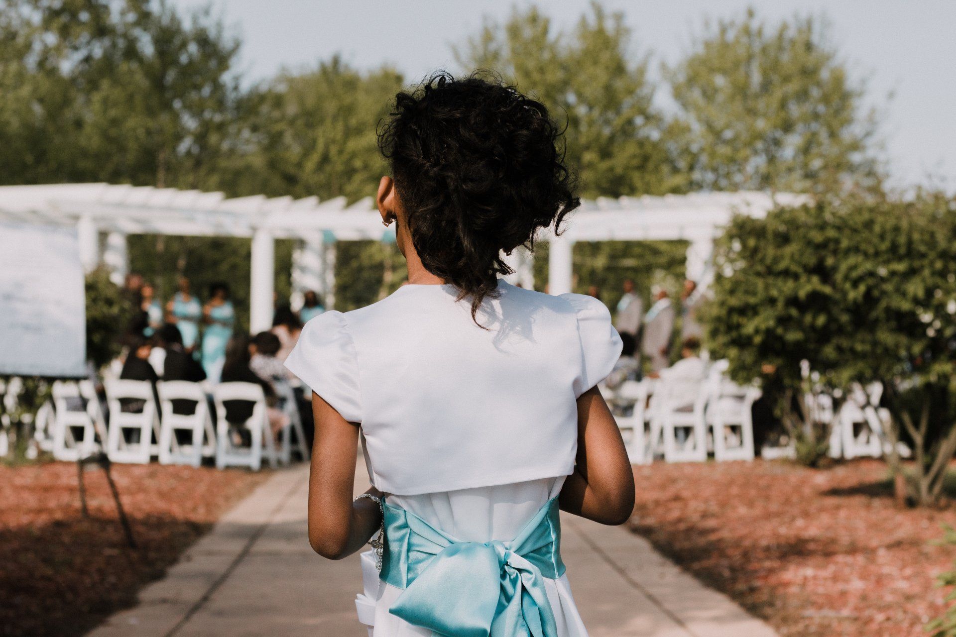 A flower girl is walking down the aisle at a wedding.