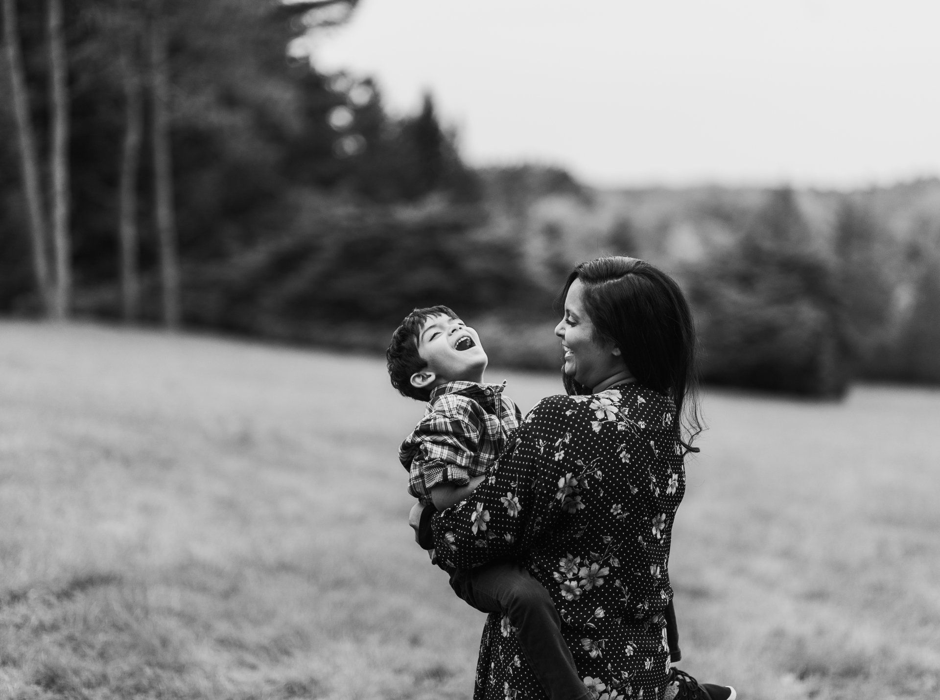 A woman is holding a child in her arms in a field.