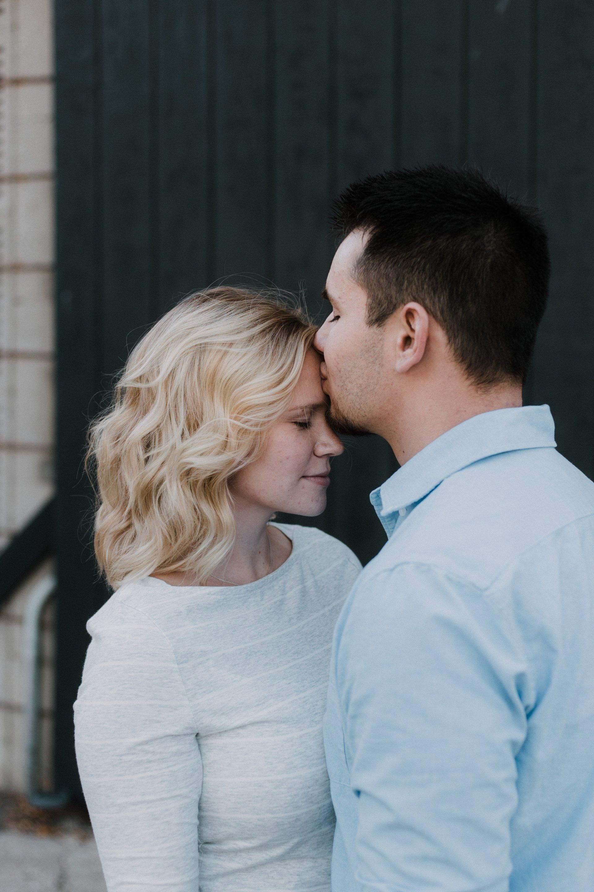 A man is kissing a woman on the forehead.