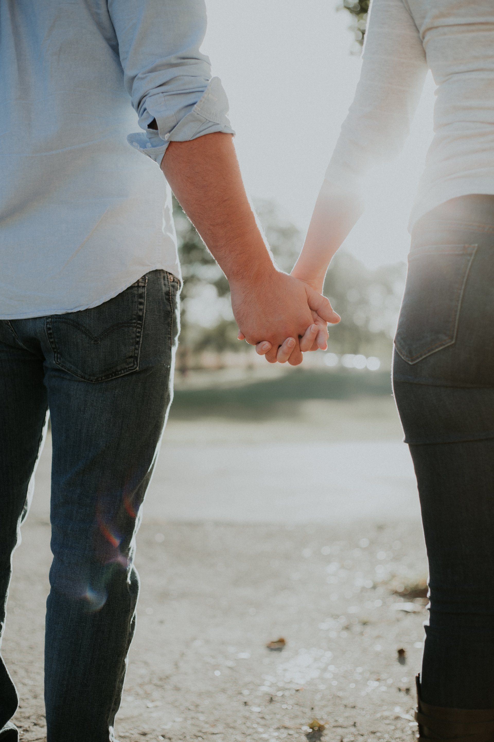 A man and a woman are holding hands while walking down the street.