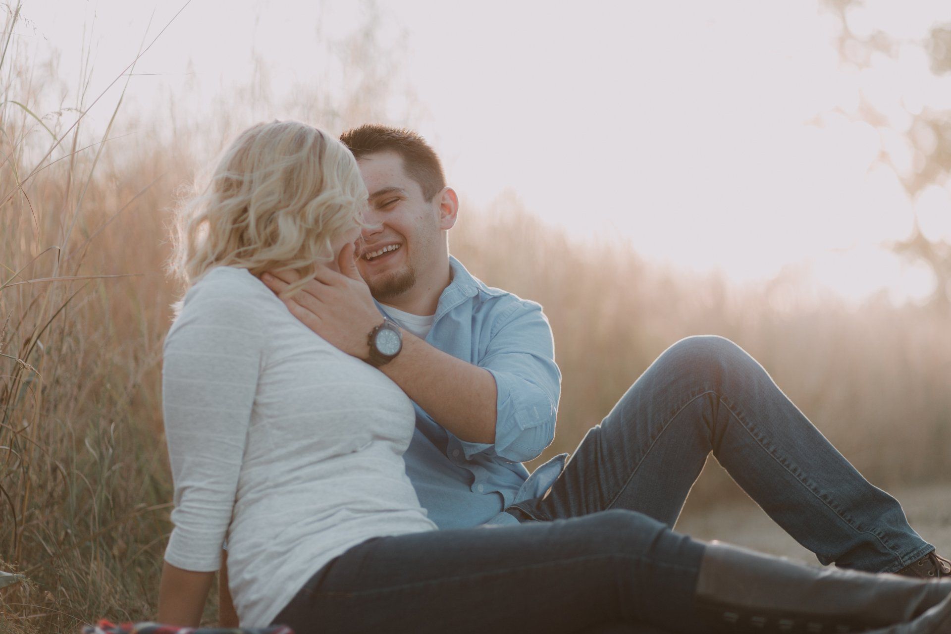 A man and a woman are sitting on a blanket in a field.
