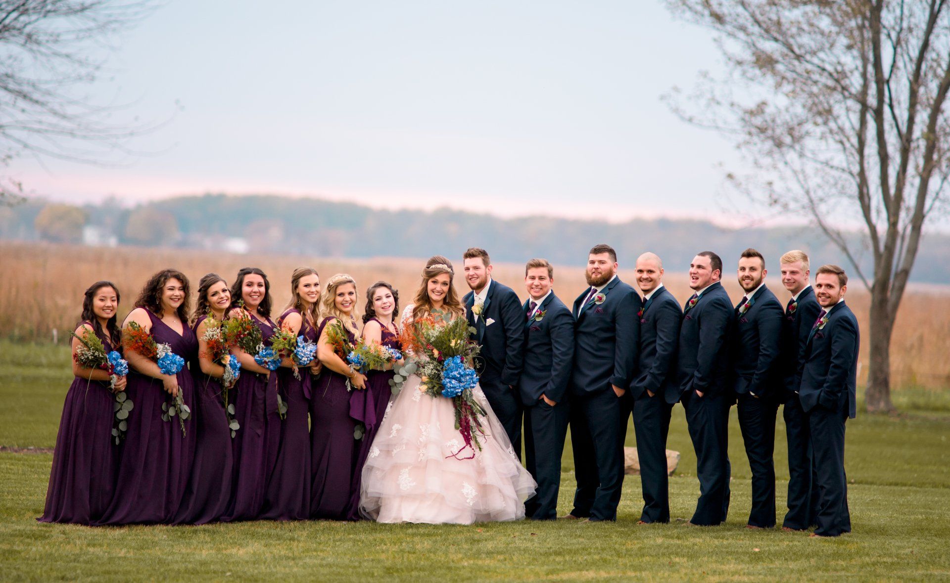 The bride and groom are posing for a picture with their wedding party.