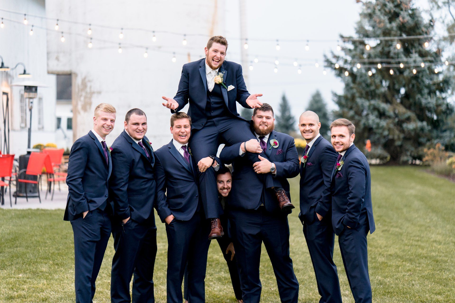 The groom is being lifted in the air by his groomsmen.
