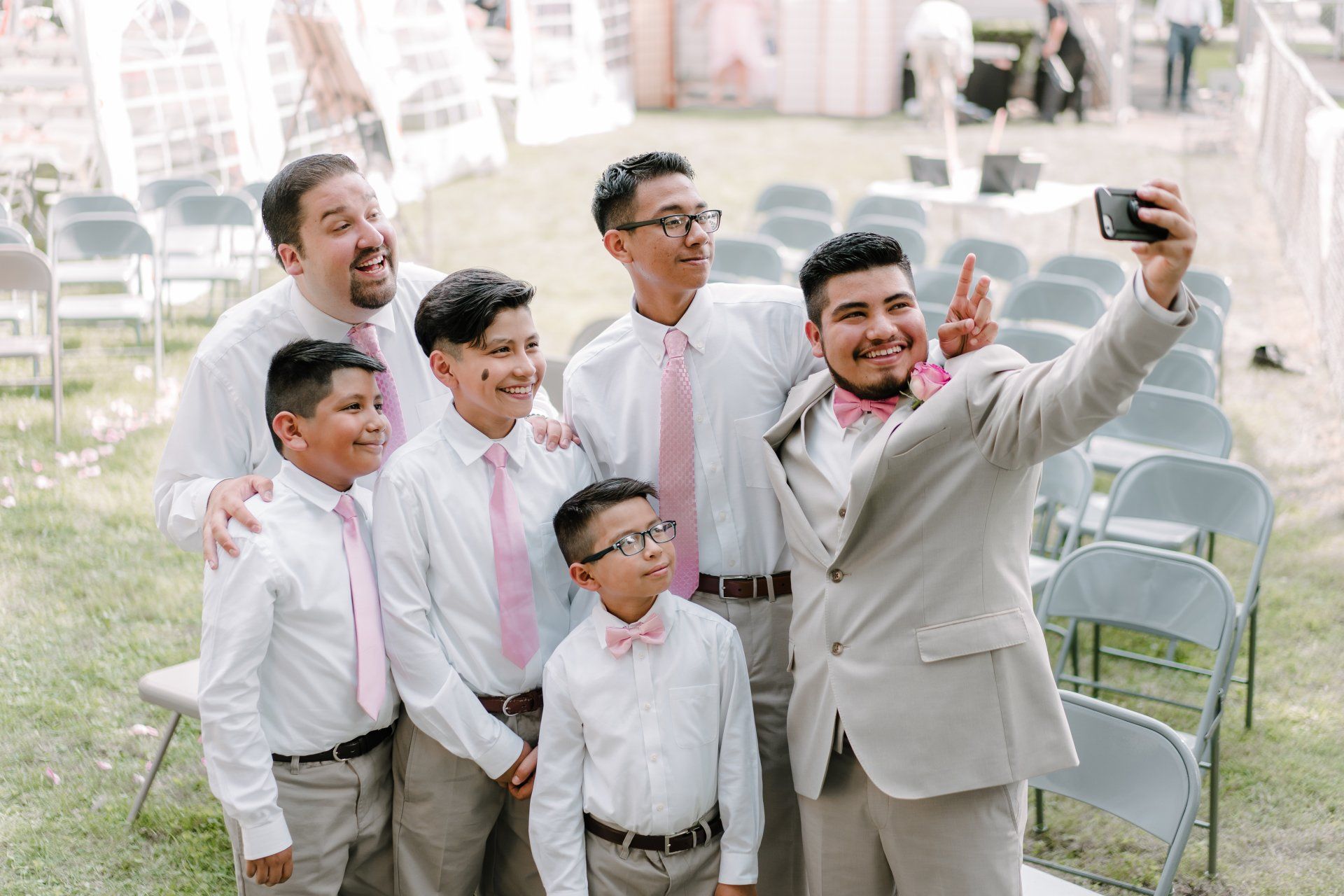 A man is taking a selfie with his groomsmen and ring bearers.