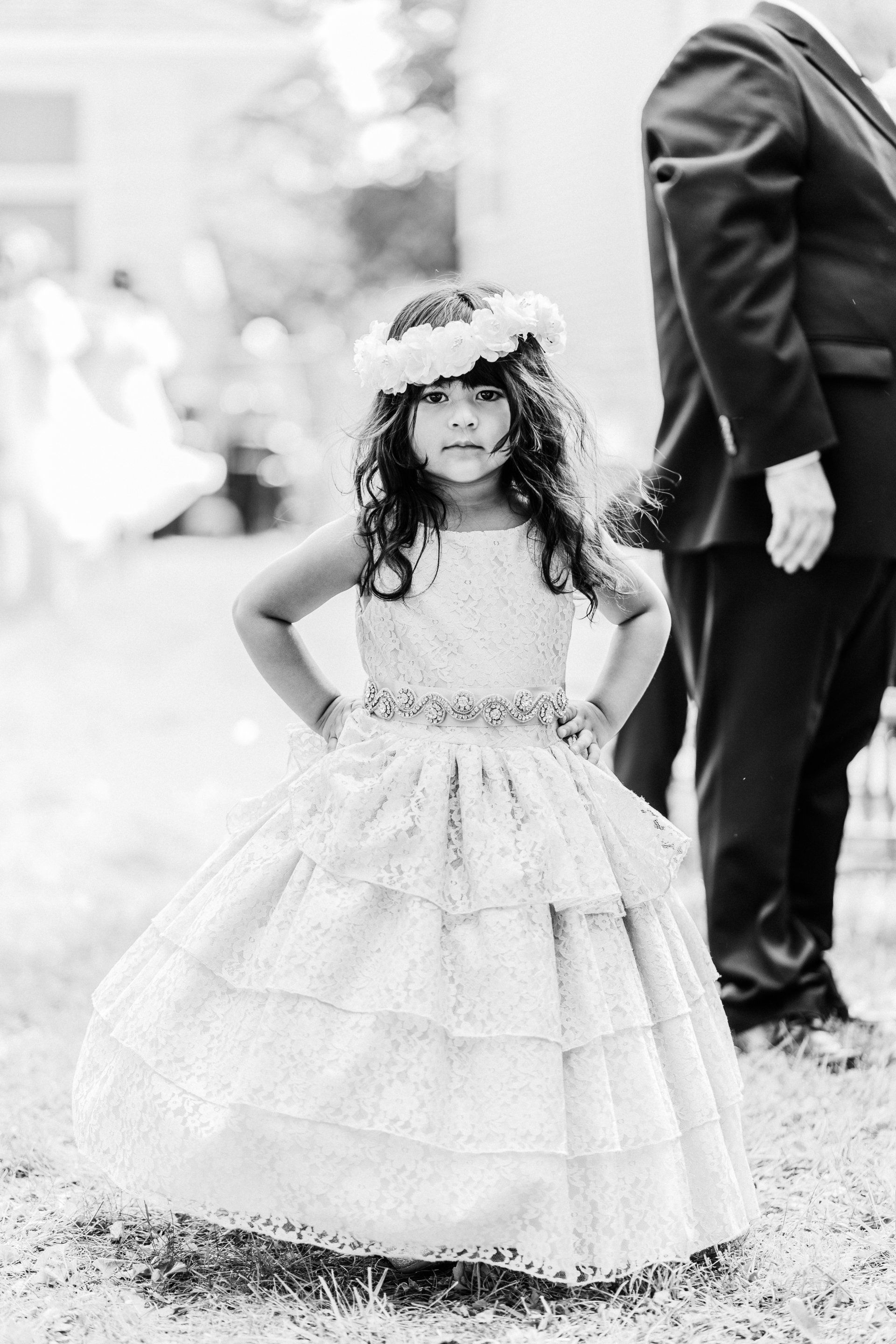 A black and white photo of a flower girl wearing a flower crown.