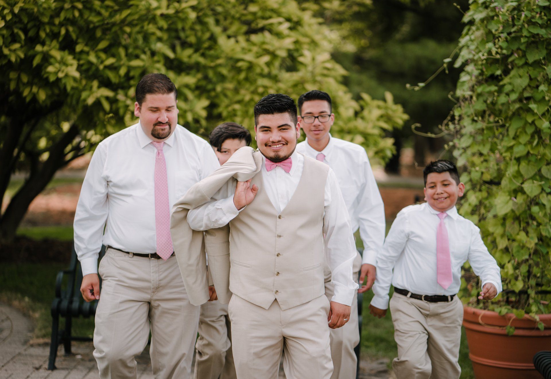 A groom and his groomsmen are walking down a sidewalk.