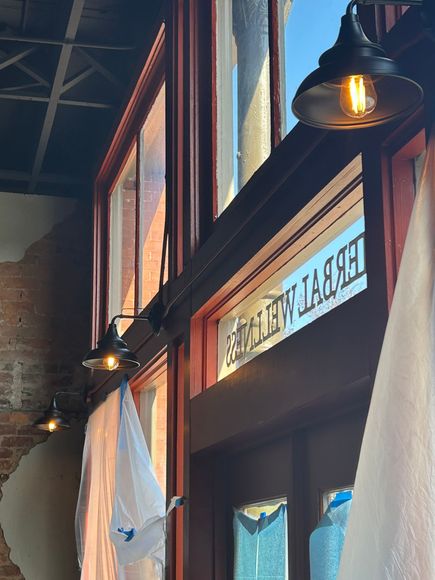 Wooden storefront under awning with warm wall lamps and a hanging sign reading “The Village.”