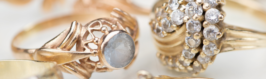 Primer plano de anillos de oro con diamantes y una piedra redonda opalescente.