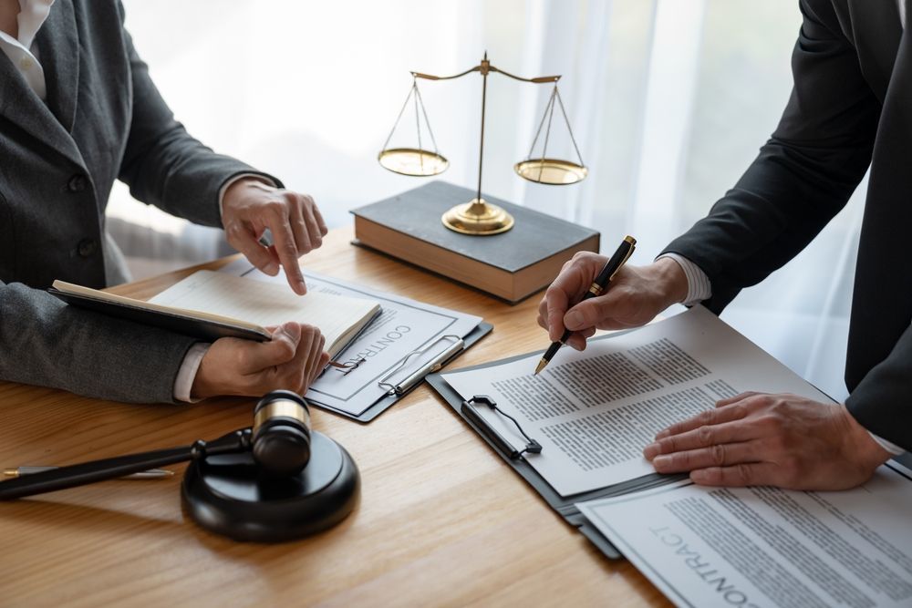 A man and a woman are sitting at a table with papers and a gavel.