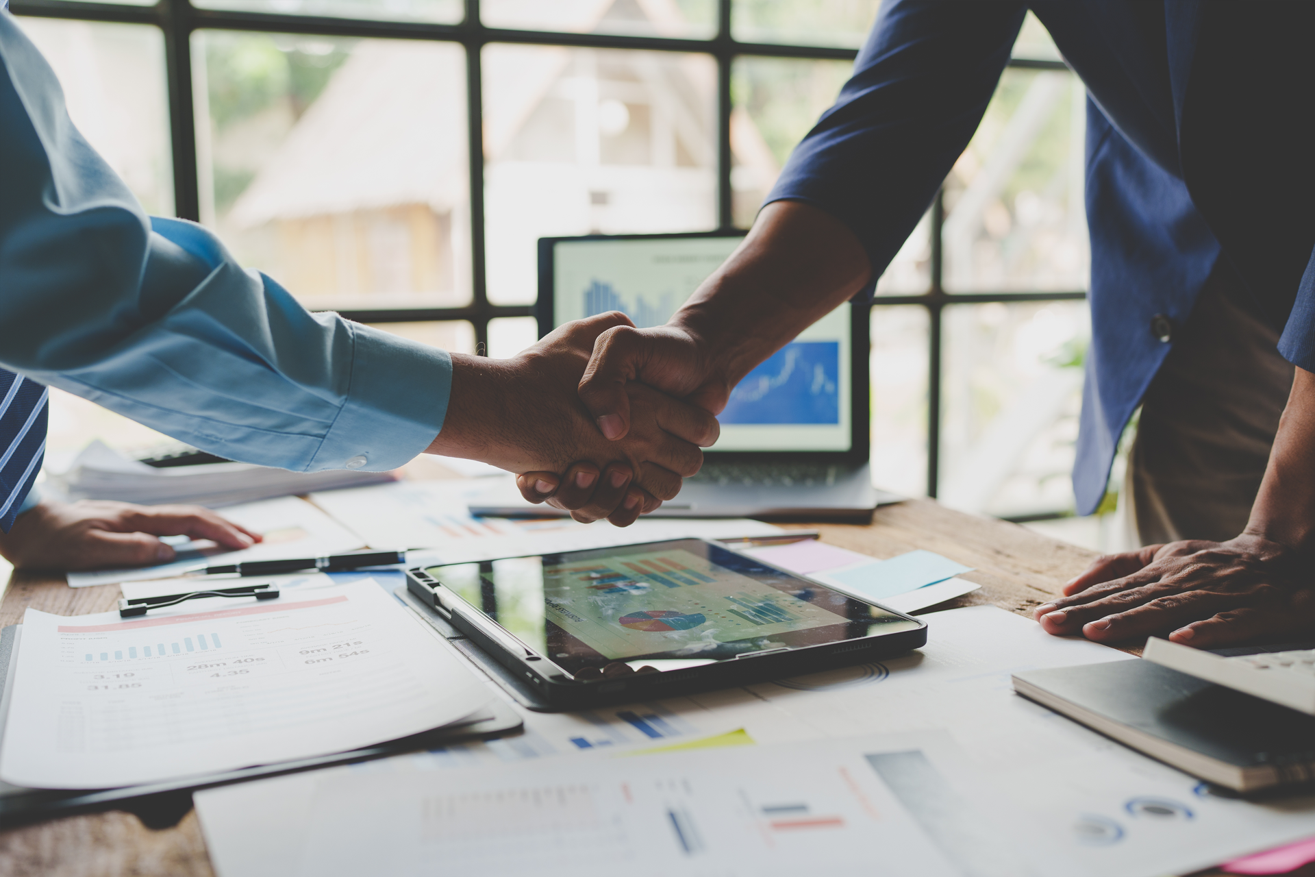 Two men are shaking hands over a table.