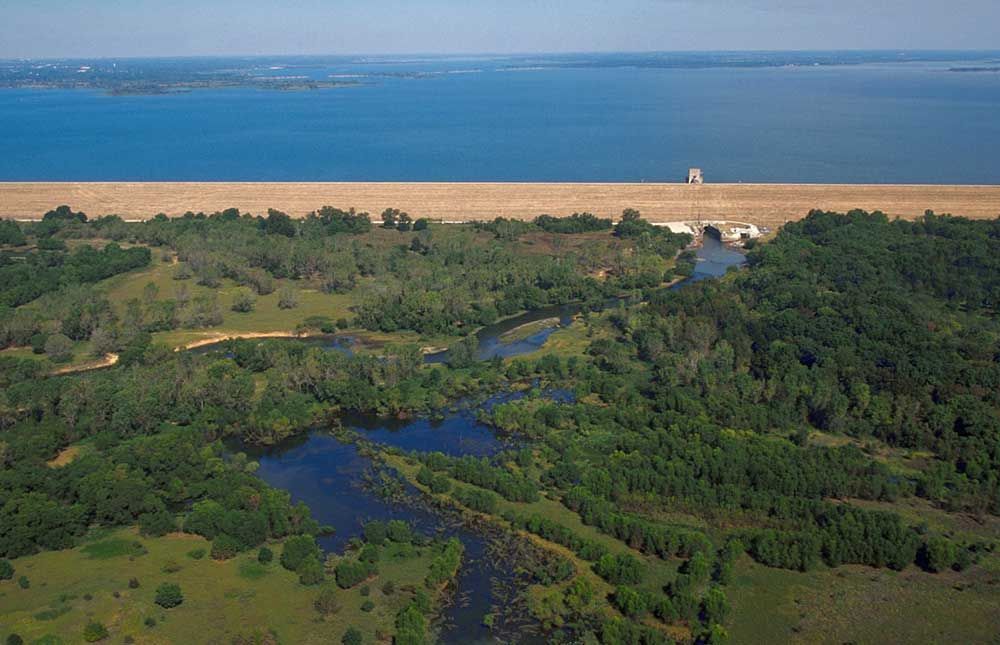 An aerial view of a lake surrounded by trees and a dam.