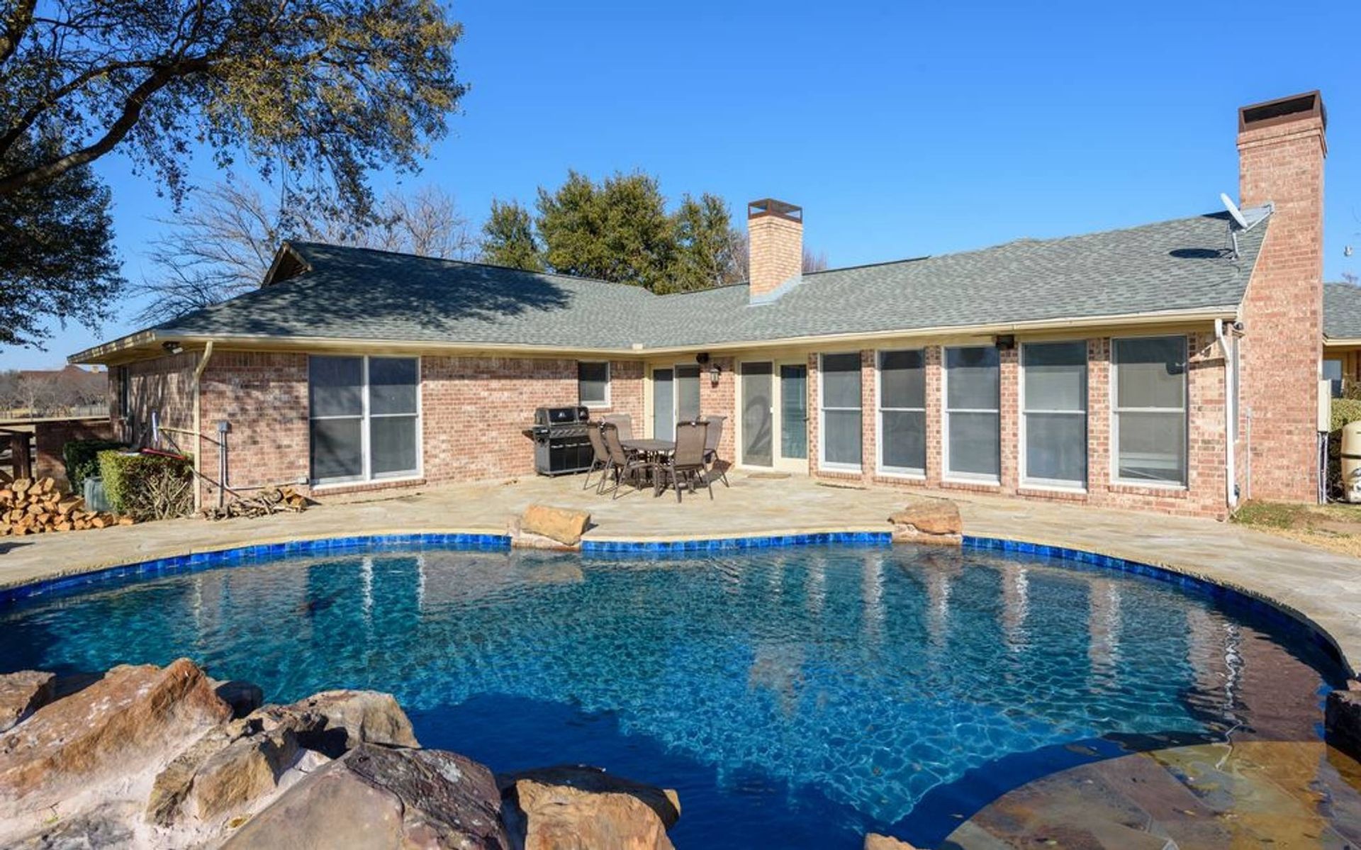 A brick house with a large swimming pool in front of it
