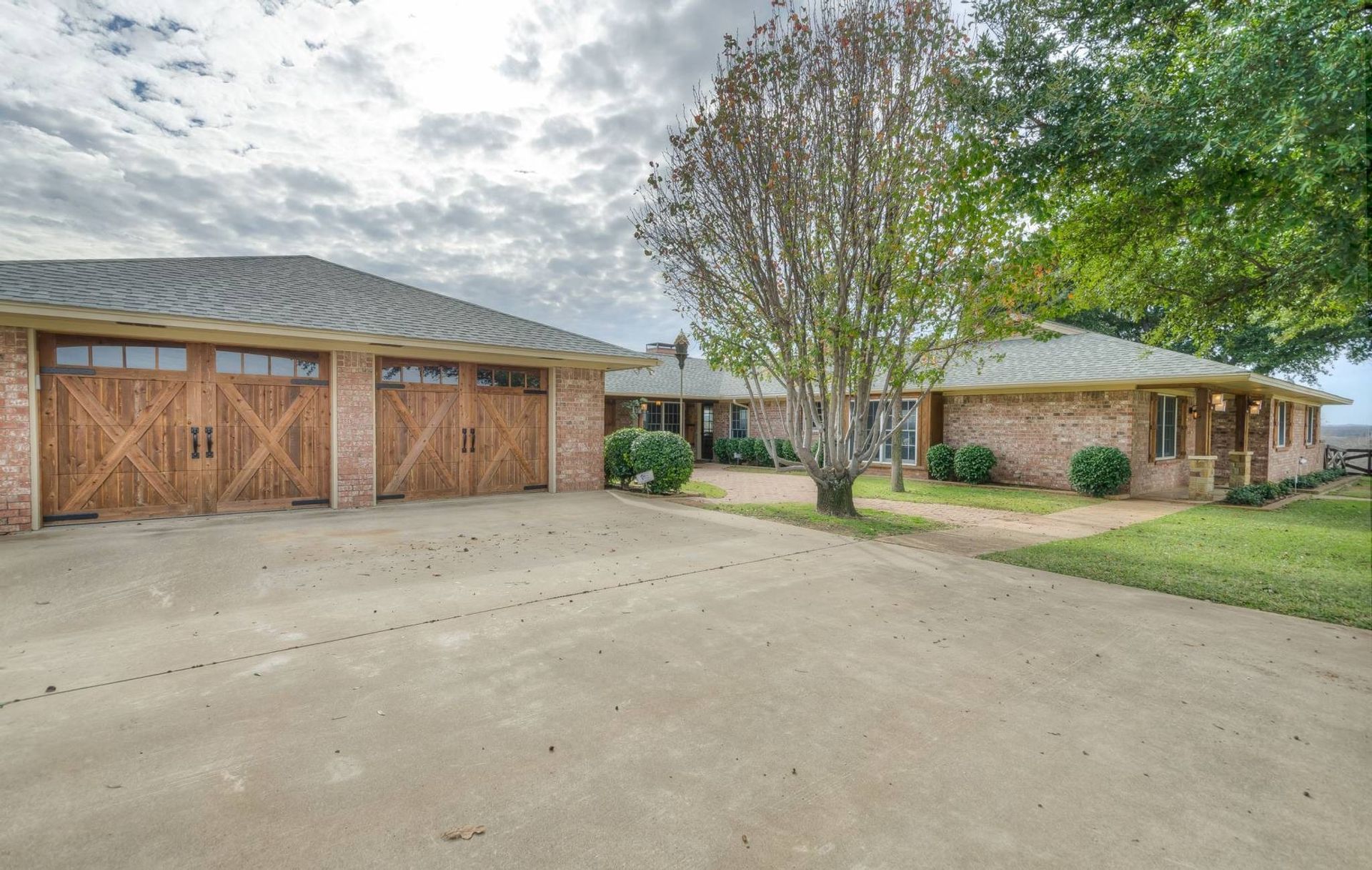 A brick house with two garage doors and a tree in front of it