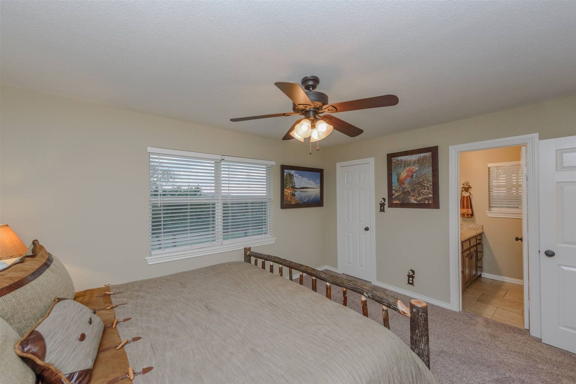 A bedroom with a bed , ceiling fan , and two windows.