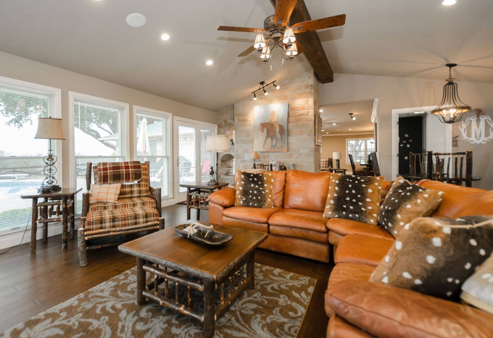 A living room with a couch , chair , coffee table and ceiling fan.
