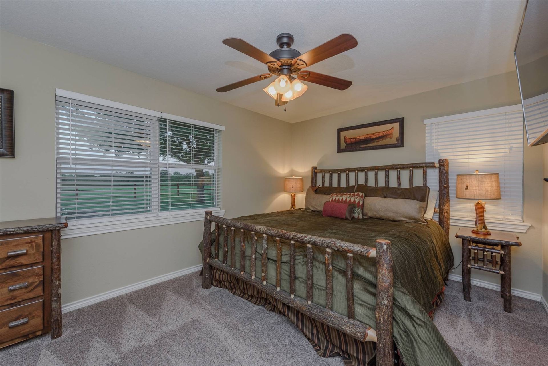 A bedroom with a bed , dresser , nightstand and ceiling fan.