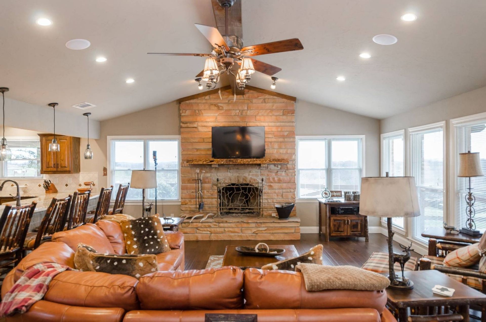 A living room with a couch , fireplace , television and ceiling fan.