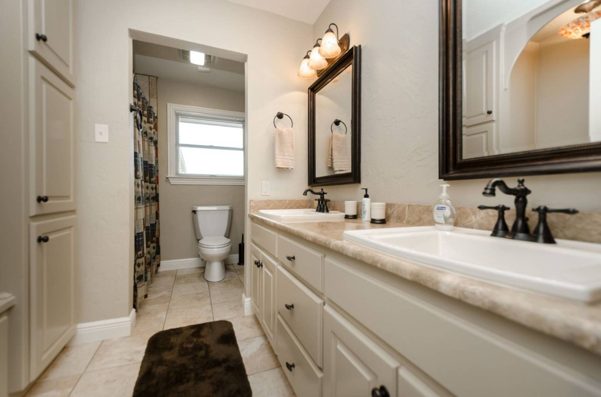 A bathroom with two sinks , a toilet and a mirror.