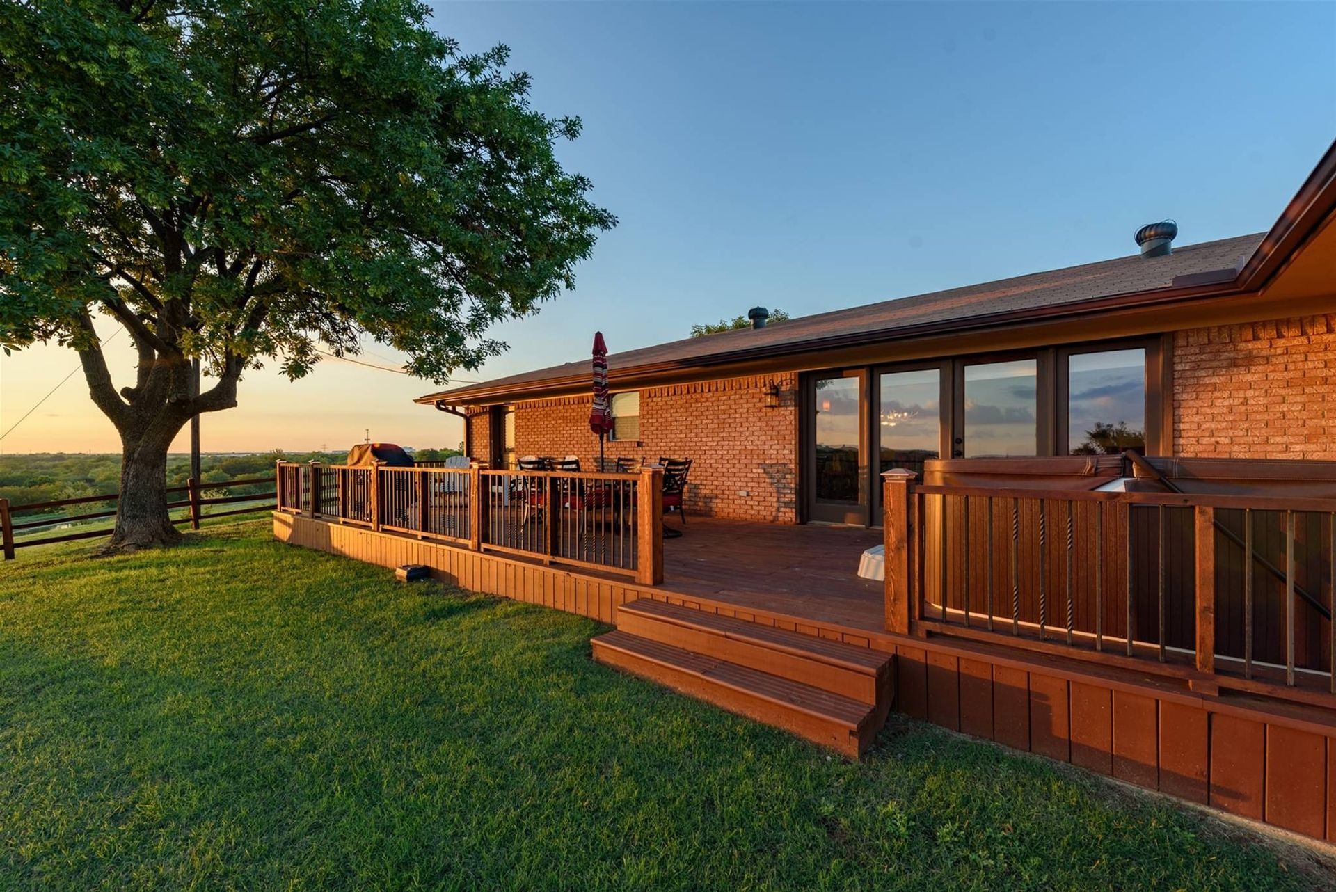A house with a large deck and a tree in the background.