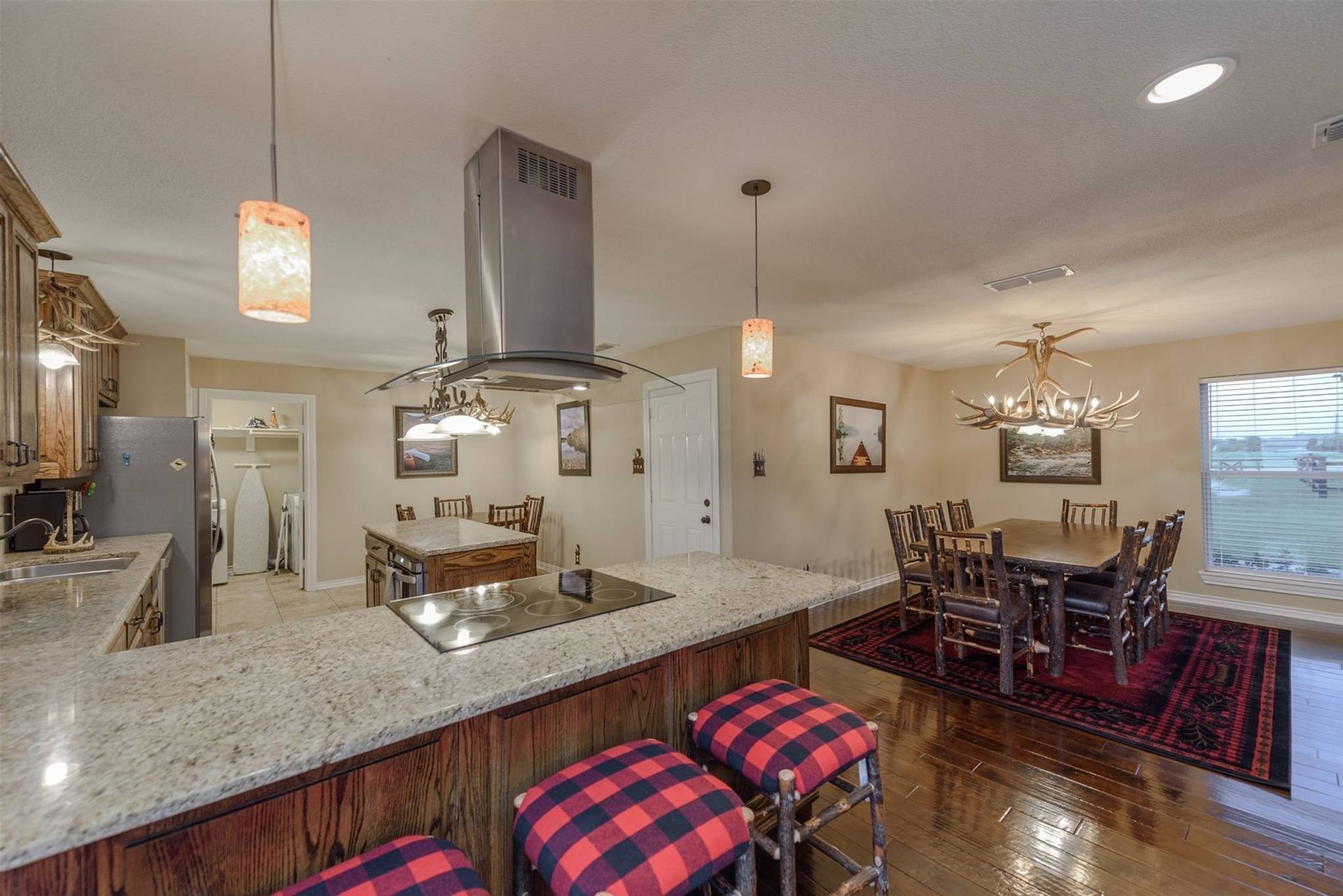 A kitchen with a stove top oven and a dining room with a table and chairs.