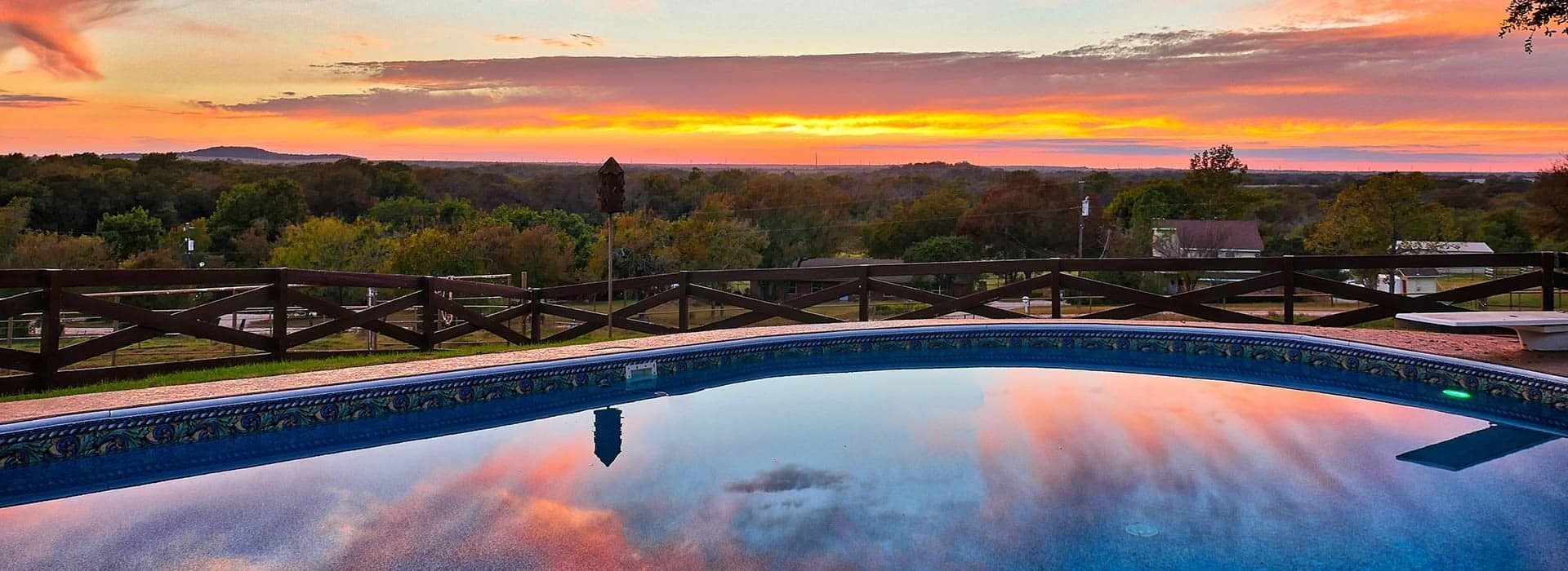 A large swimming pool with a sunset in the background.