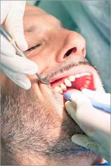 Man receiving treatment for Cosmetic Crown Lengthening to prepare for a crown by Nassau County Periodontist, Dr. Marichia Attalla in Williston Park, NY 11596