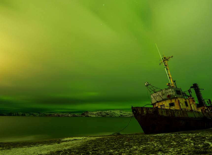 Fishing boat under Northern Lights in Tromsø, Norway