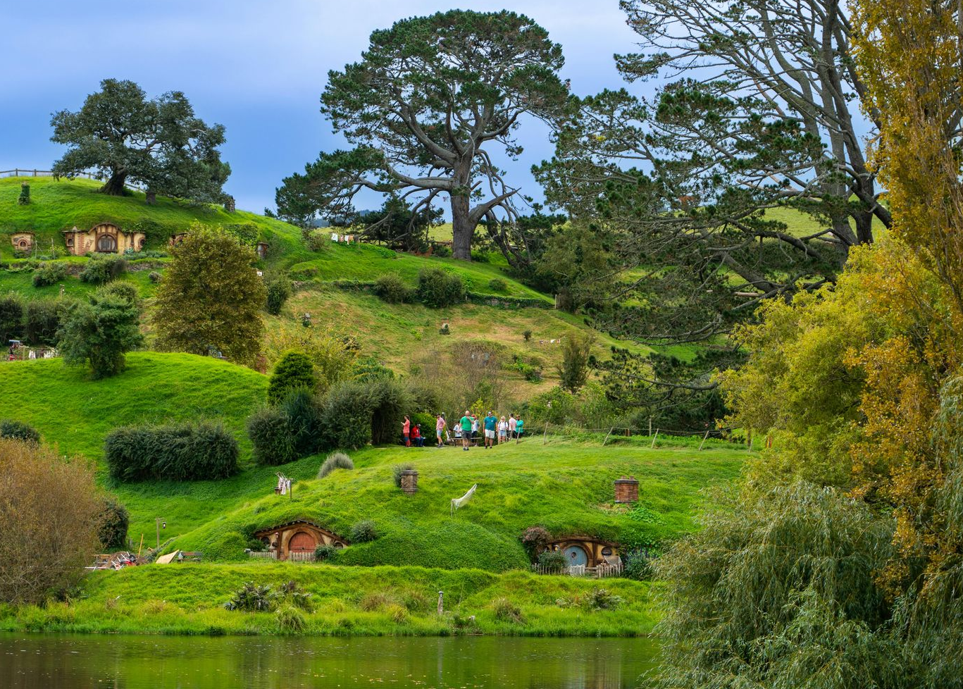 Lord of the Rings tour group exploring Hobbiton with rolling hills and hobbit holes, popular New Zealand Middle-earth destination