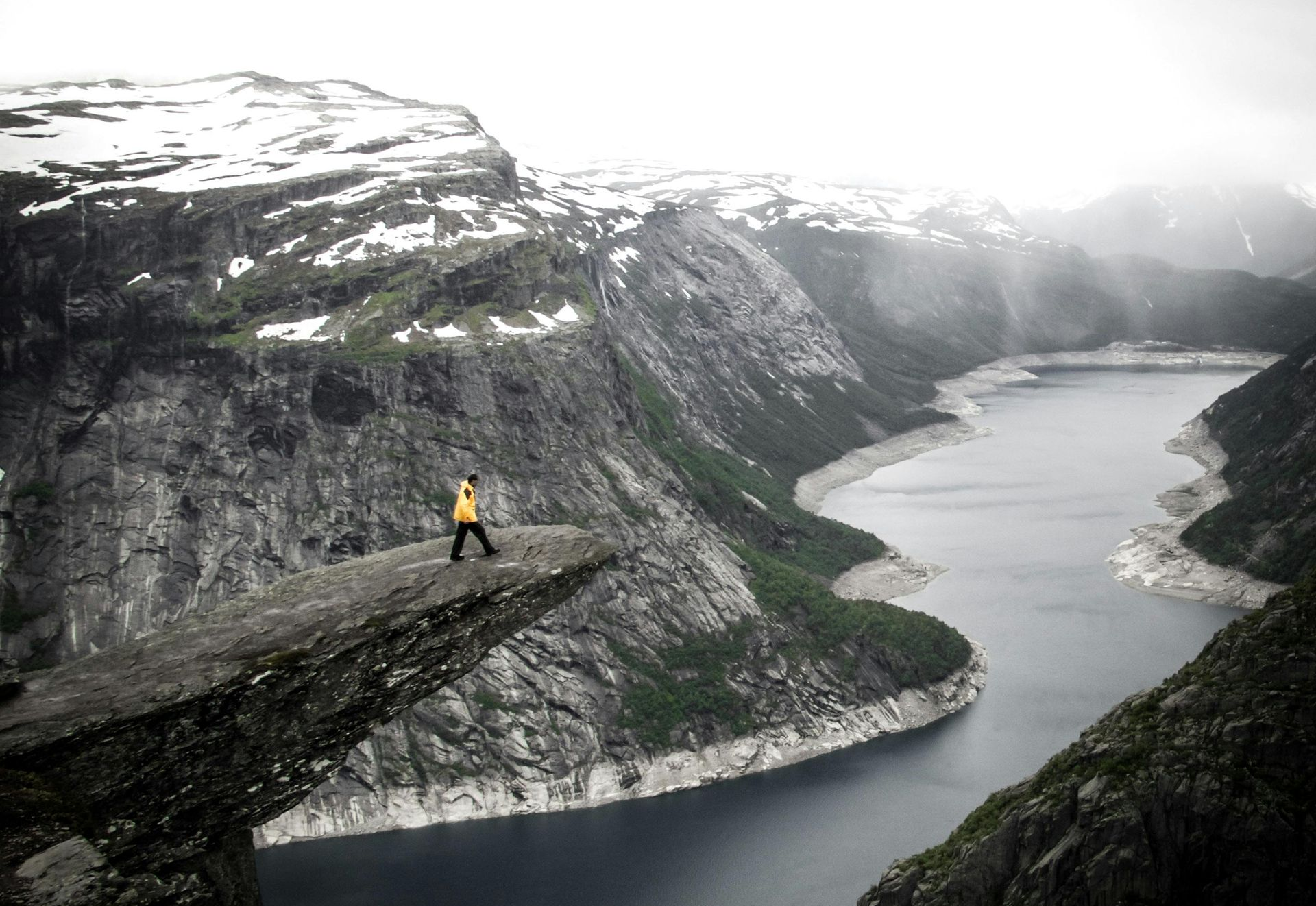 Traveler on Trolltunga cliff in Norway overlooking fjord.