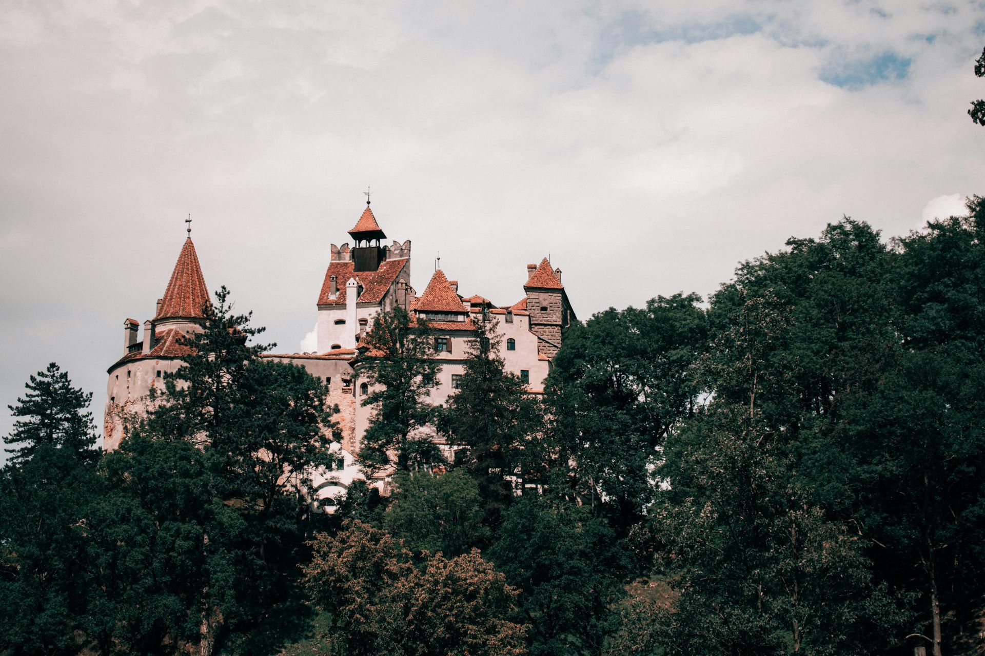 Bran Castle in Romania in cloudy weather, linked to Dracula legend.