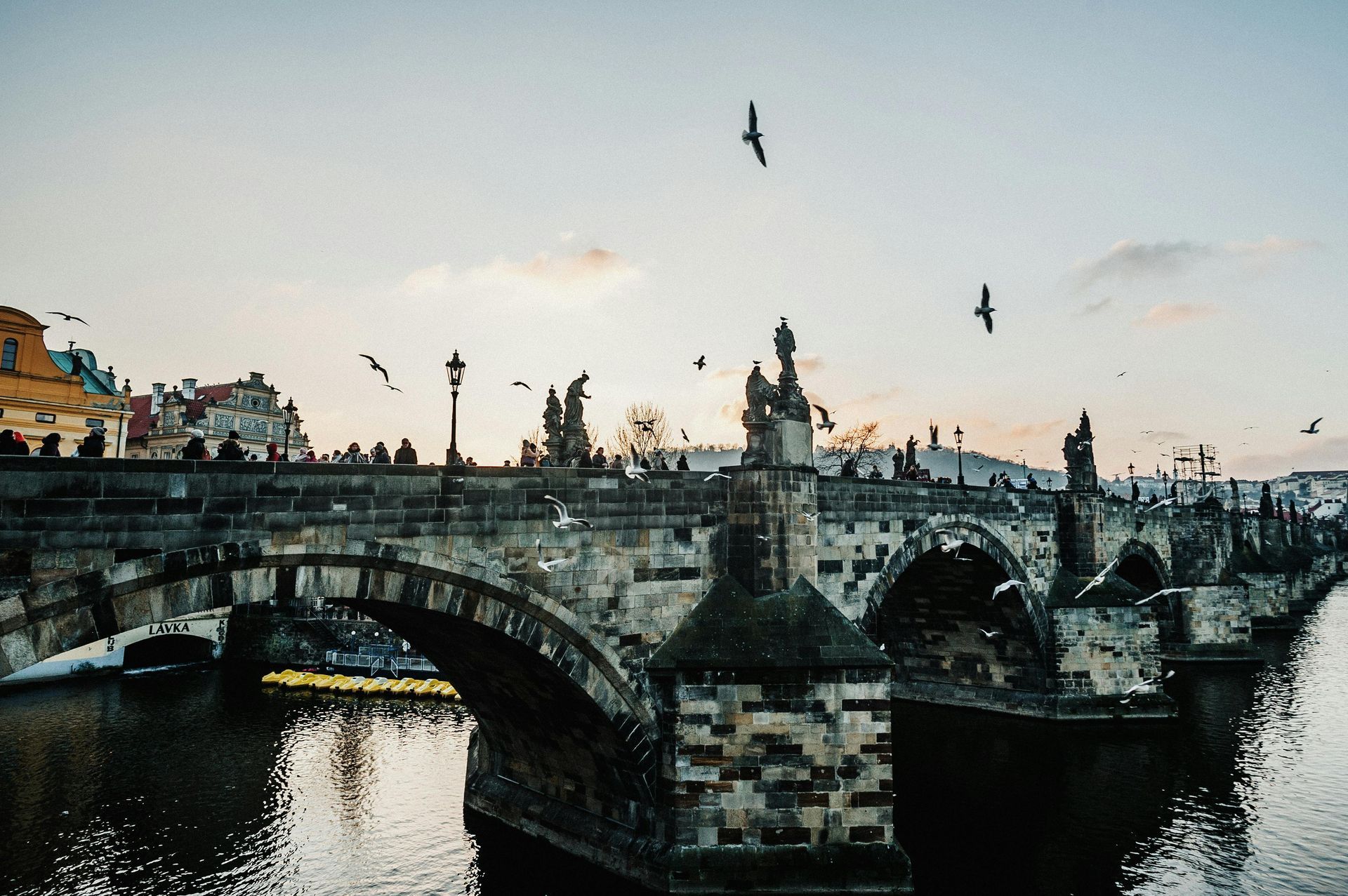 Couple walking across Prague’s Charles Bridge at sunrise