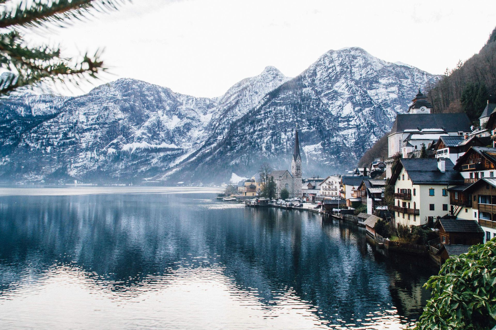 Hallstatt Austria in winter, alpine village covered in snow reflecting in mountain lake, winter fantasy travel