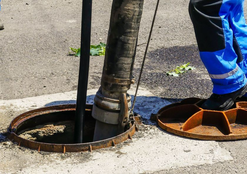 A Worker Operates a Large Hose Into an Open Manhole on a Paved Road — All Class Liquid Waste in Dalby, QLD