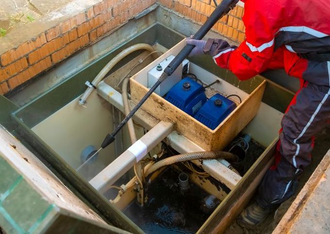 A Person in a Red Jacket Cleans a Septic System With a Power Washer — All Class Liquid Waste in Oakey, QLD