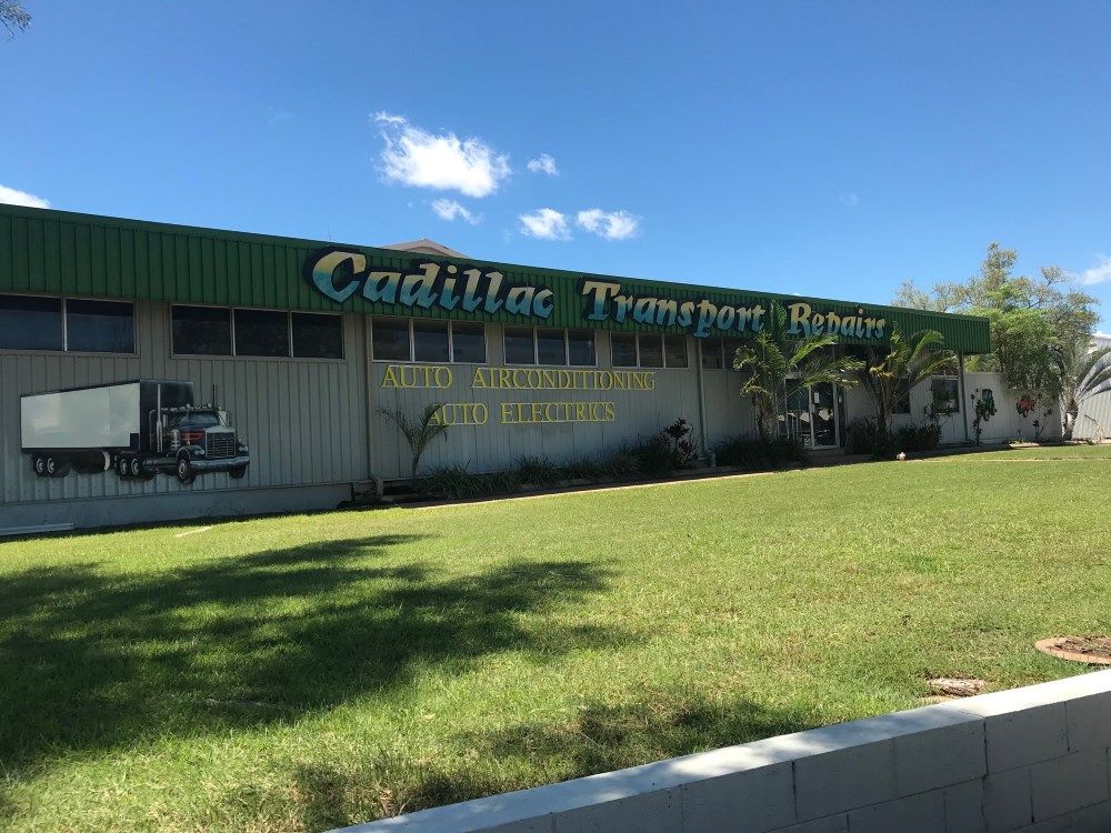 Cadillac Transport Repairs building with a truck mural on the side. Green roof and sign, with grass in front — Cadillac Transport Repairs in Winnellie, NT