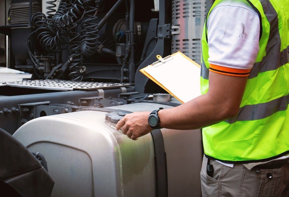 A Person Is Inspecting A Truck Close To The Gas Tank — Cadillac Transport Repairs in Winnellie, NT