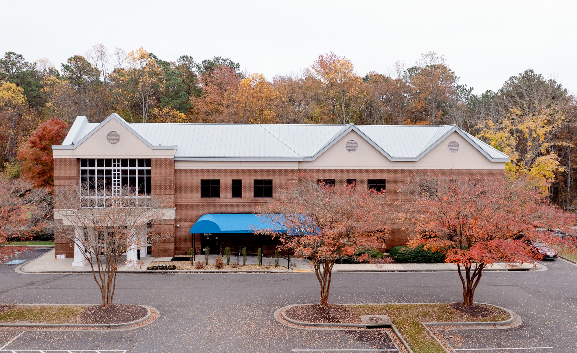 Two-story davita dialysis & richmond nephrology brick building with a blue awning and large windows.